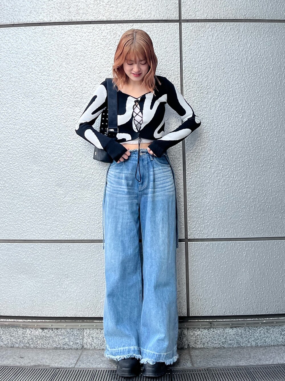 ブラック系のスニーカー、ブルー系のデニムパンツ、ホワイト系のキャミソールを着用したレディースの冬コーディネートの2枚目の写真