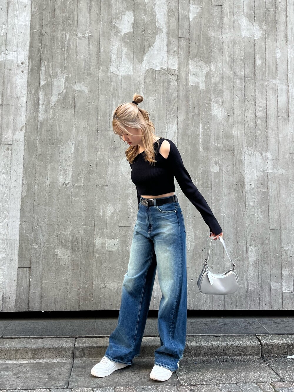 ブルー系のデニムパンツ、シルバー系のハンドバッグ、ブラック系のニット/セーターを着用したレディースの春コーディネートの2枚目の写真