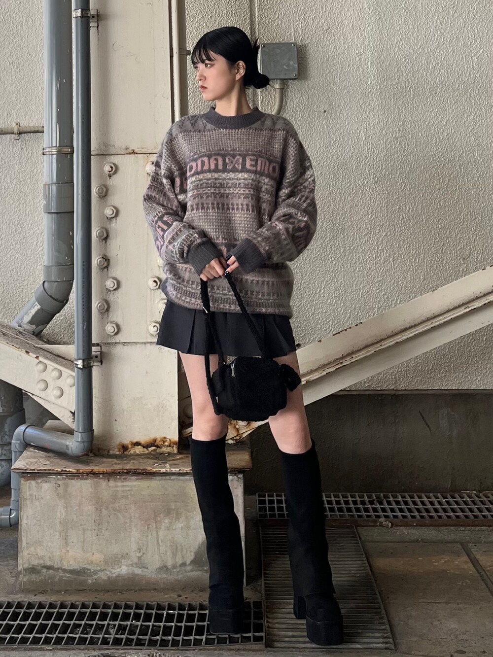グレー系のスカート、ピンク系のニット/セーター、ブラック系のブーツを着用したレディースの冬コーディネートの2枚目の写真