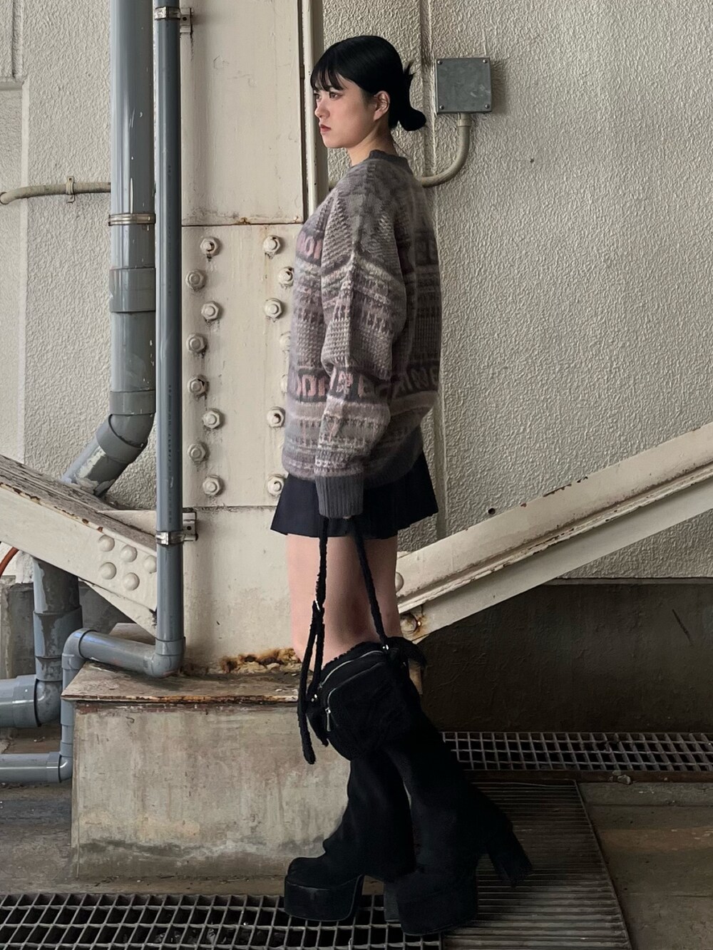 グレー系のスカート、ピンク系のニット/セーター、ブラック系のブーツを着用したレディースの冬コーディネートの3枚目の写真