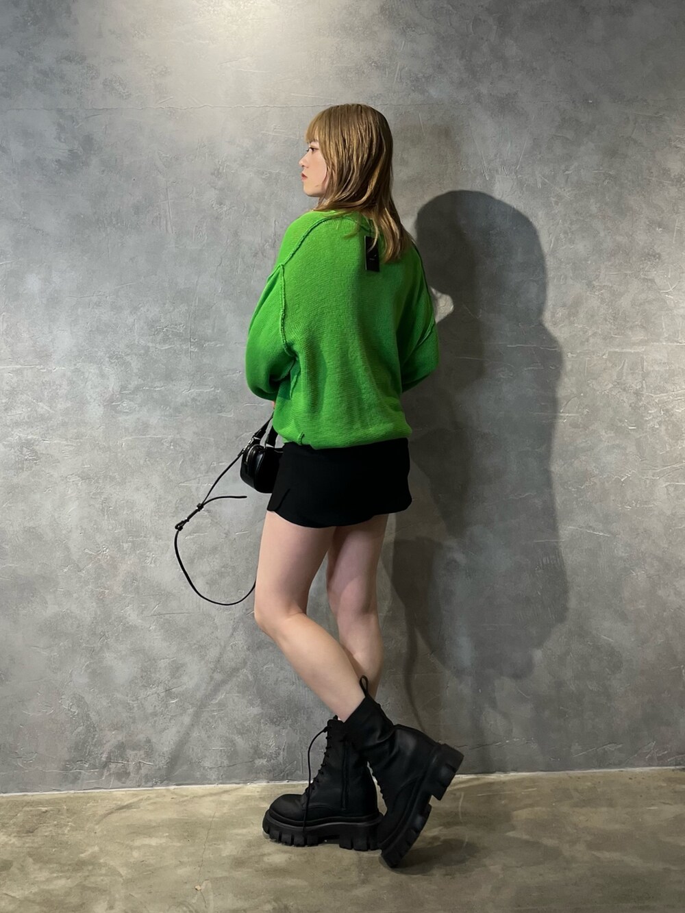 グリーン系のカーディガン/ボレロ、ブラック系のブーツ、ブラック系のスカートを着用したレディースの冬コーディネートの2枚目の写真