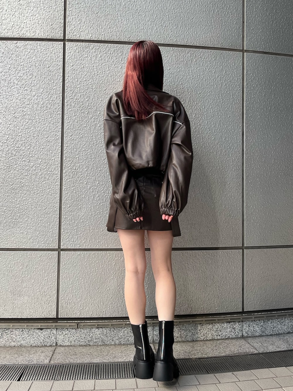 ブラウン系のスカート、ブラック系のニット/セーター、ブラウン系のブルゾンを着用したレディースの冬コーディネートの4枚目の写真