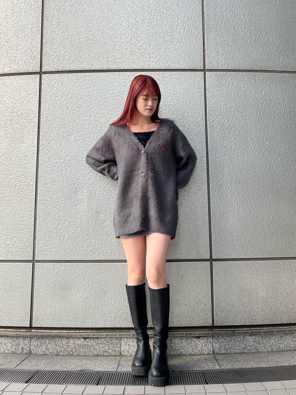 グレー系のカーディガン/ボレロ、グレー系のスカート、ブラック系のブーツを着用したレディースの秋コーディネートの2枚目の写真