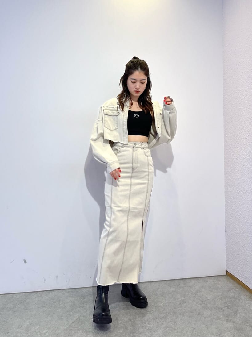 ホワイト系のデニムジャケット、ホワイト系のスカート、ブラック系のブーツを着用したレディースの夏コーディネートの2枚目の写真