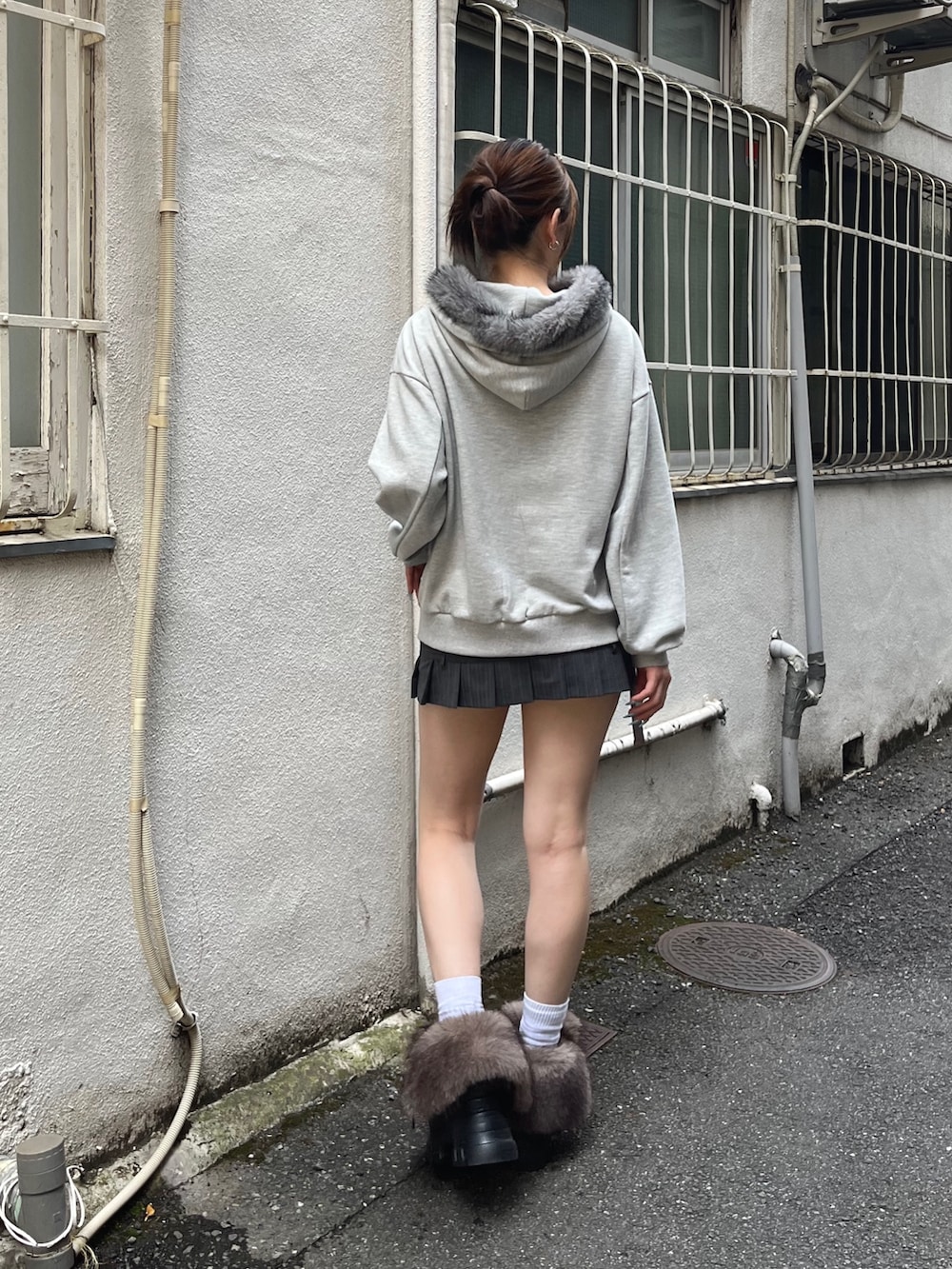 グレー系のパーカー、グレー系のスカート、ブラック系のブーツを着用したレディースの秋コーディネートの3枚目の写真