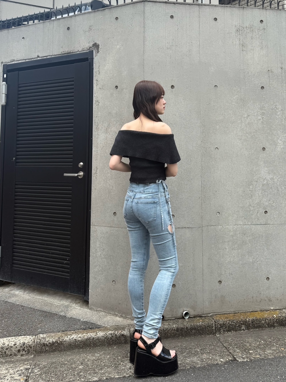 ブルー系のデニムパンツ、ブラック系のサンダル、ブラック系のニット/セーターを着用したレディースの春コーディネートの2枚目の写真