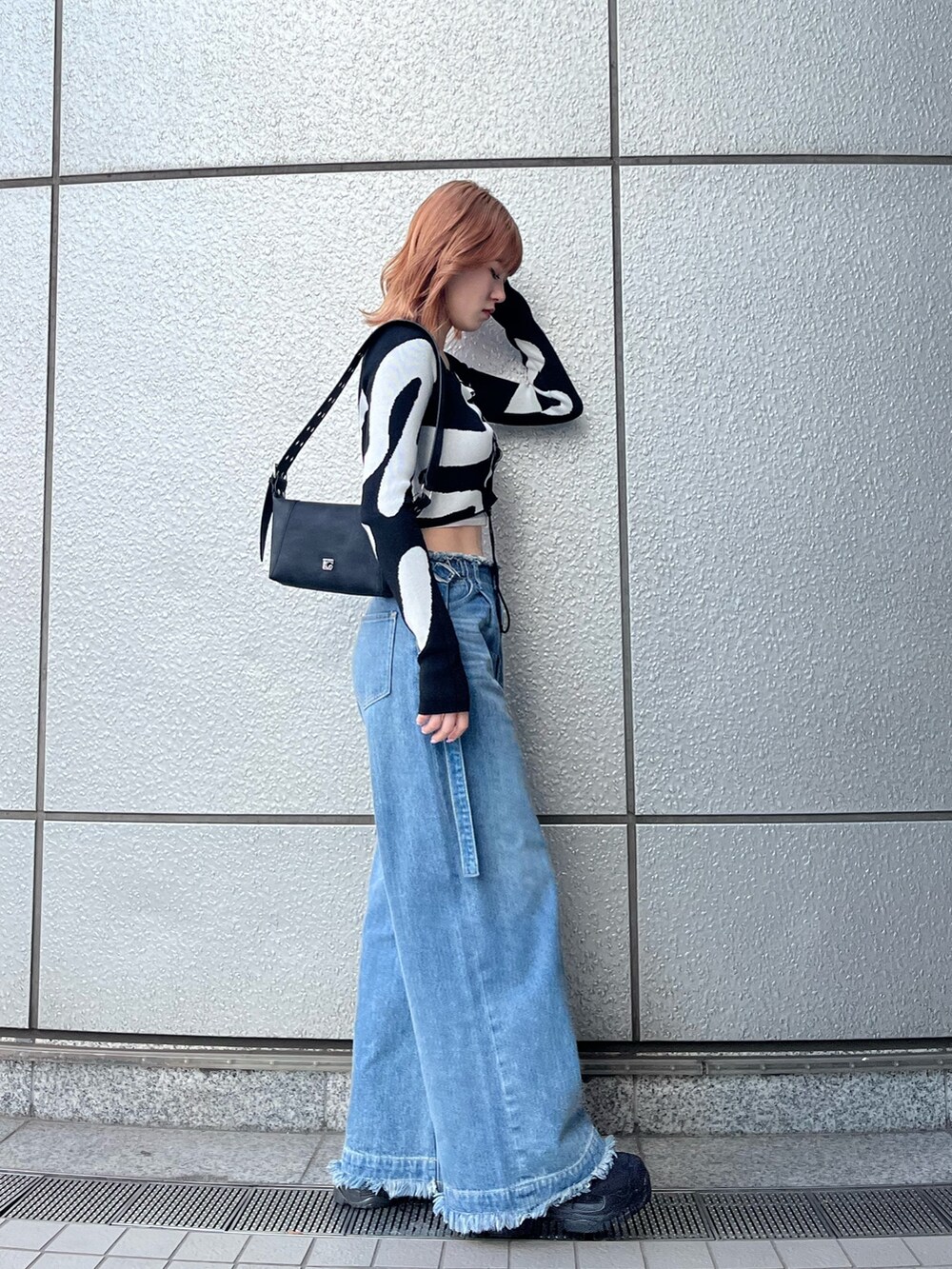 ブラック系のスニーカー、ブルー系のデニムパンツ、ホワイト系のキャミソールを着用したレディースの冬コーディネートの4枚目の写真