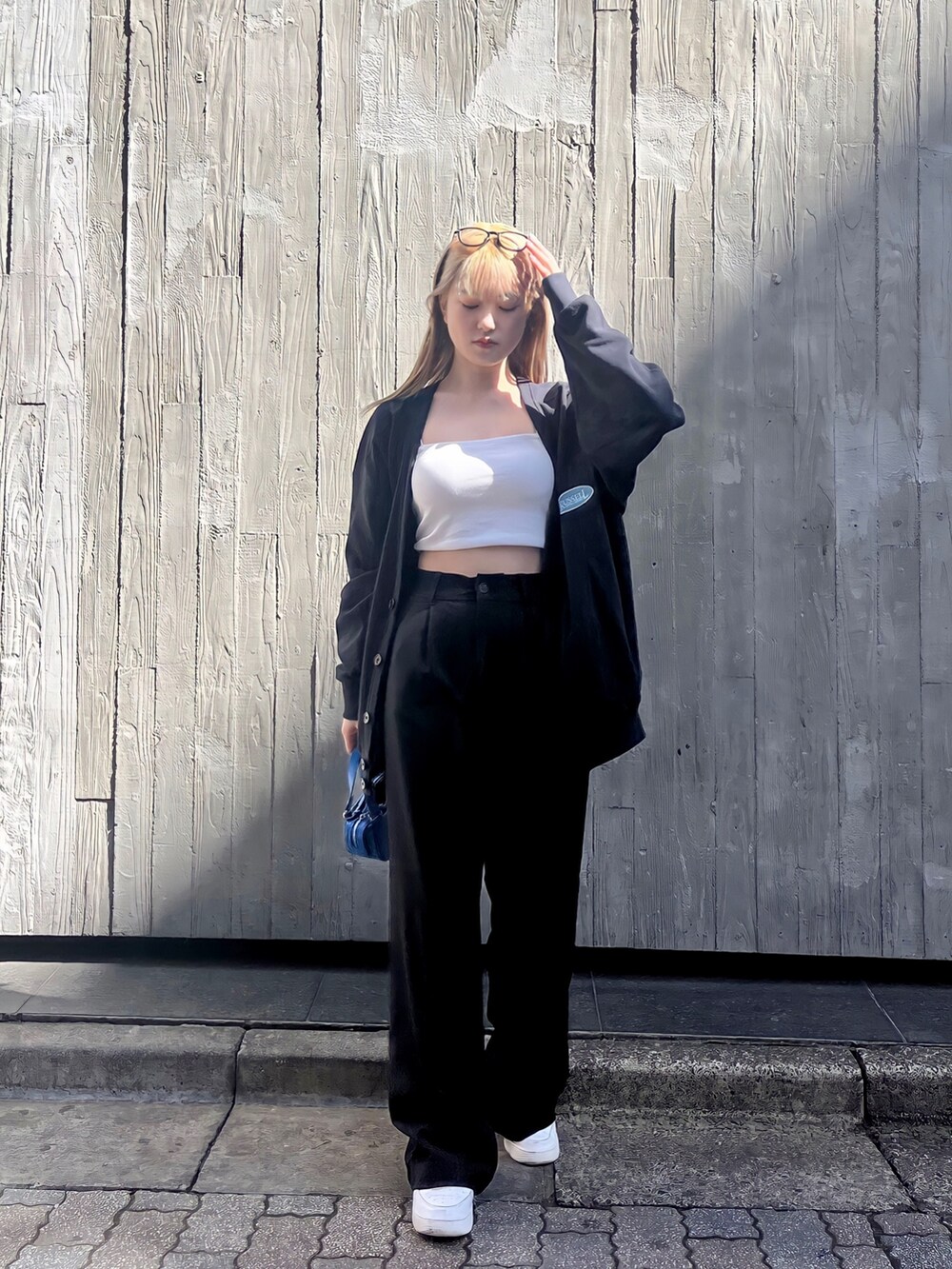 ホワイト系のキャミソール、ブラック系のカーディガン/ボレロ、ブルー系のハンドバッグを着用したレディースの春コーディネートの2枚目の写真