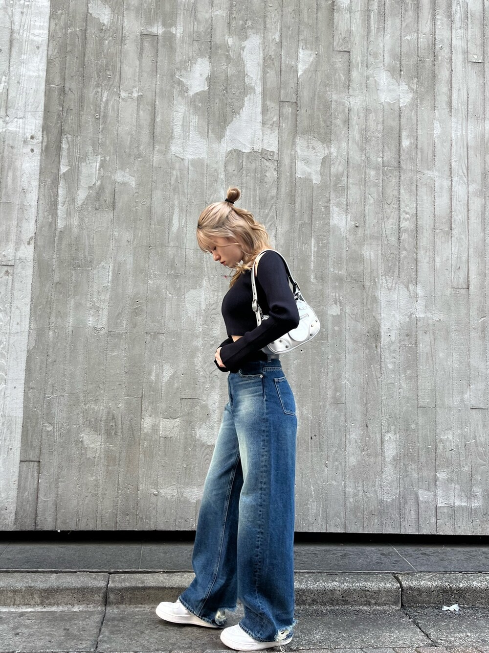 ブルー系のデニムパンツ、シルバー系のハンドバッグ、ブラック系のニット/セーターを着用したレディースの春コーディネートの3枚目の写真