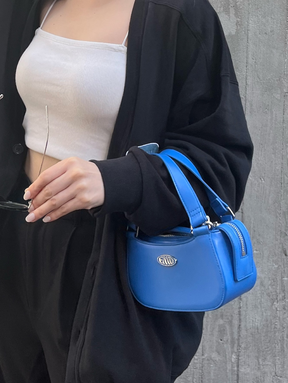 ホワイト系のキャミソール、ブラック系のカーディガン/ボレロ、ブルー系のハンドバッグを着用したレディースの春コーディネートの7枚目の写真