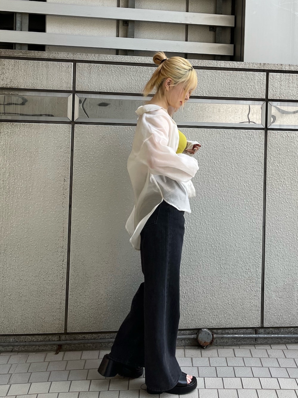 ブラック系のデニムパンツ、ブラック系のサンダル、イエロー系のタンクトップを着用したレディースの春コーディネートの5枚目の写真