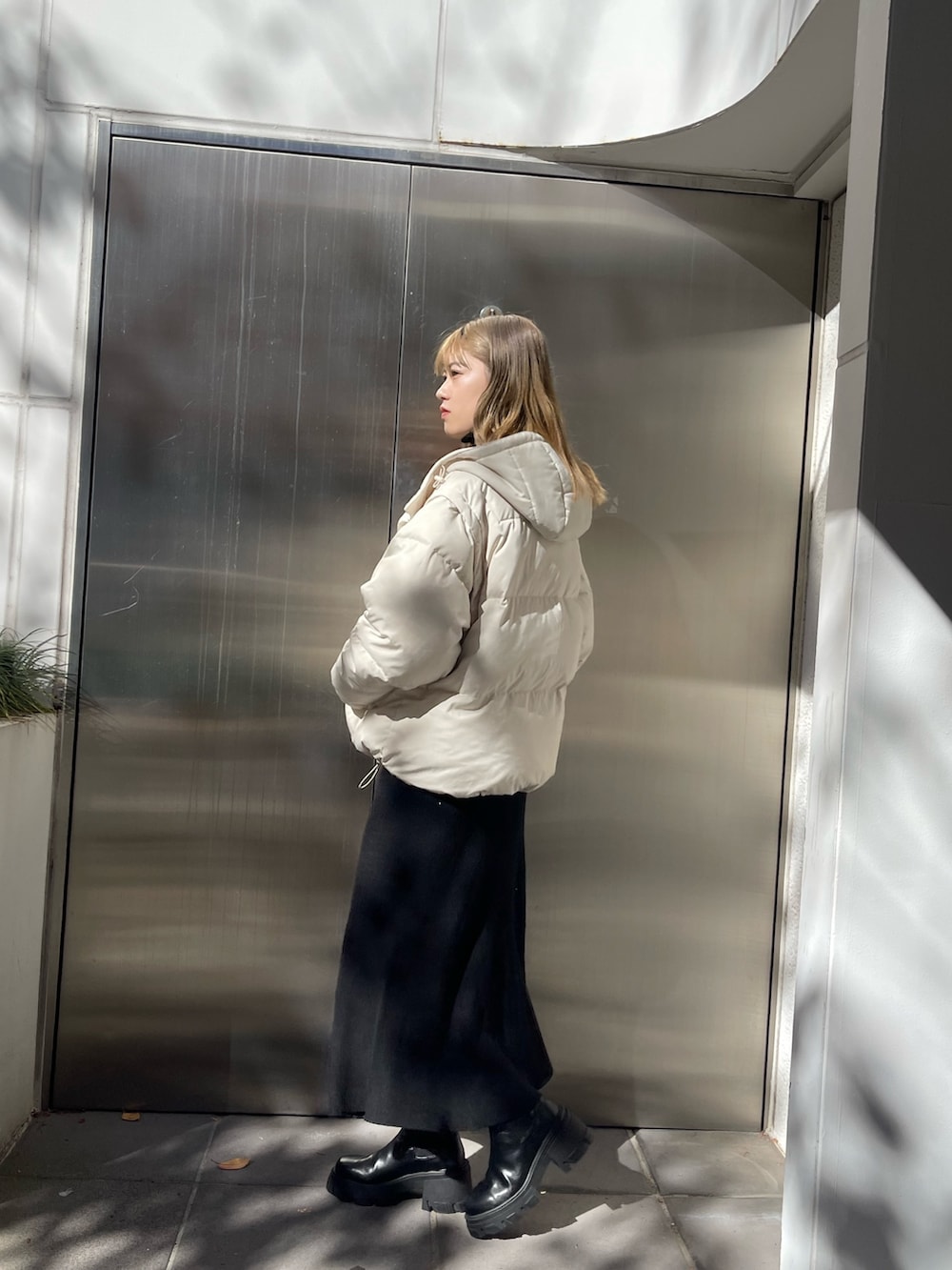 ホワイト系のダウンジャケット/コート、ブラック系のワンピース、ブラック系のブーツを着用したレディースの秋コーディネートの2枚目の写真