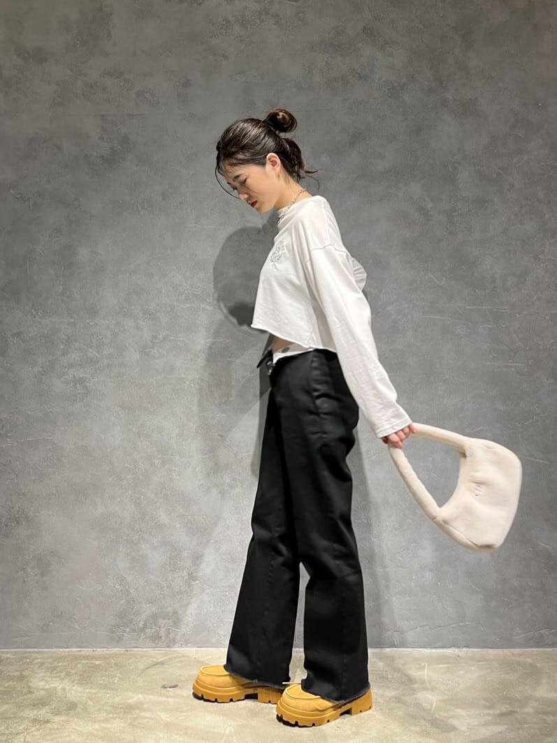 ホワイト系のハンドバッグ、ホワイト系のTシャツ/カットソー、ブラウン系のブーツを着用したレディースの秋コーディネートの3枚目の写真