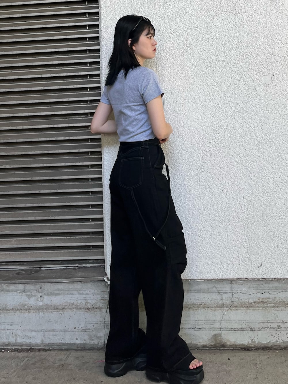 ブラック系のデニムパンツ、グレー系のTシャツ/カットソー、ブラック系のサンダルを着用したレディースの夏コーディネートの2枚目の写真