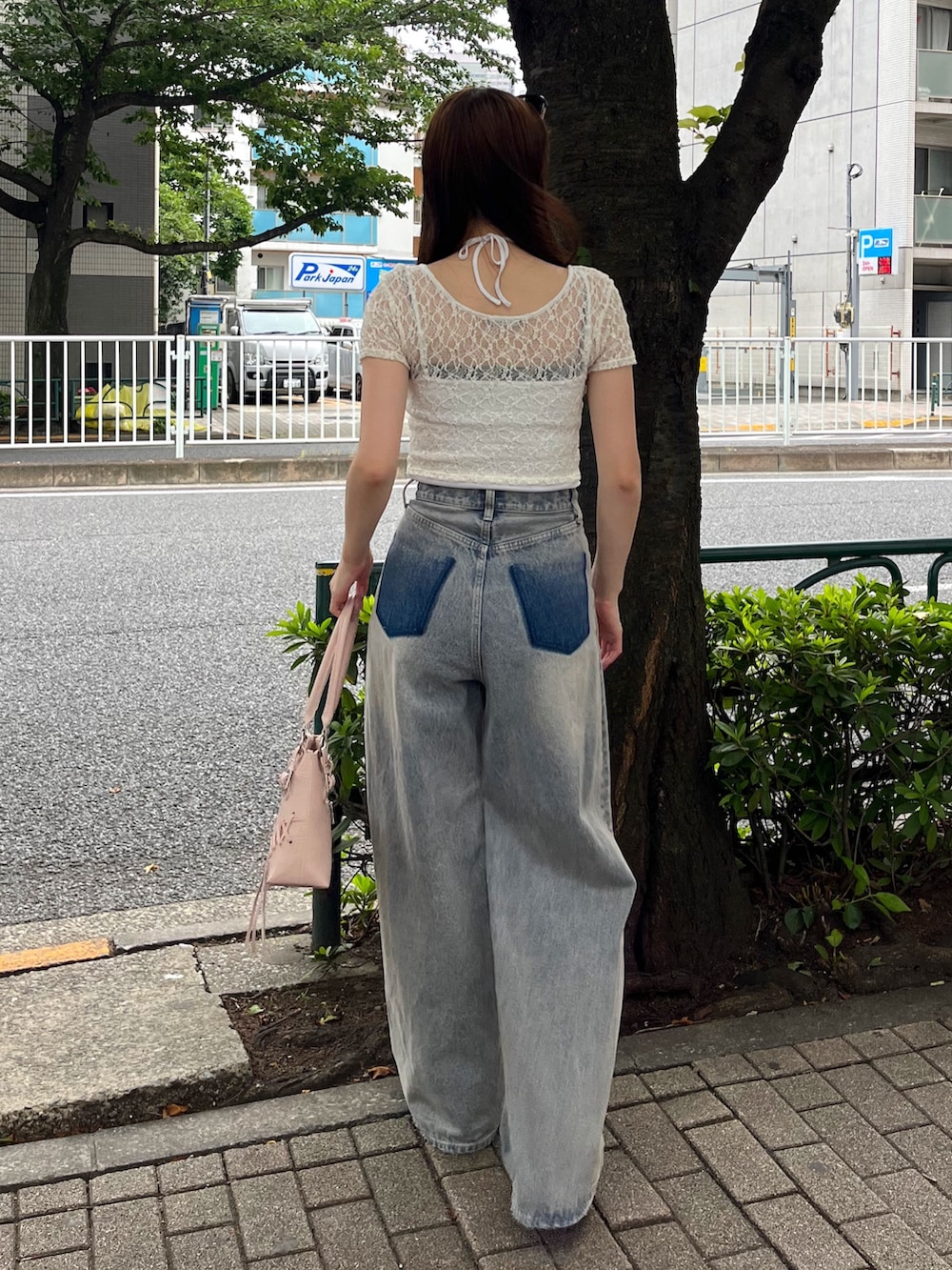 ブルー系のデニムパンツ、ブラウン系のスニーカー、ピンク系のショルダーバッグを着用したレディースの夏コーディネートの3枚目の写真