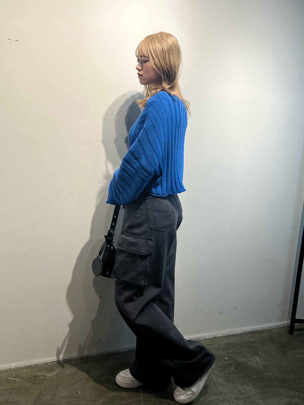 ブラック系のハンドバッグ、ブラック系のデニムパンツ、ブルー系のニット/セーターを着用したレディースの冬コーディネートの3枚目の写真