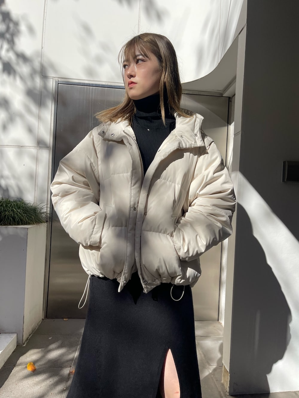 ホワイト系のダウンジャケット/コート、ブラック系のワンピース、ブラック系のブーツを着用したレディースの秋コーディネートの4枚目の写真