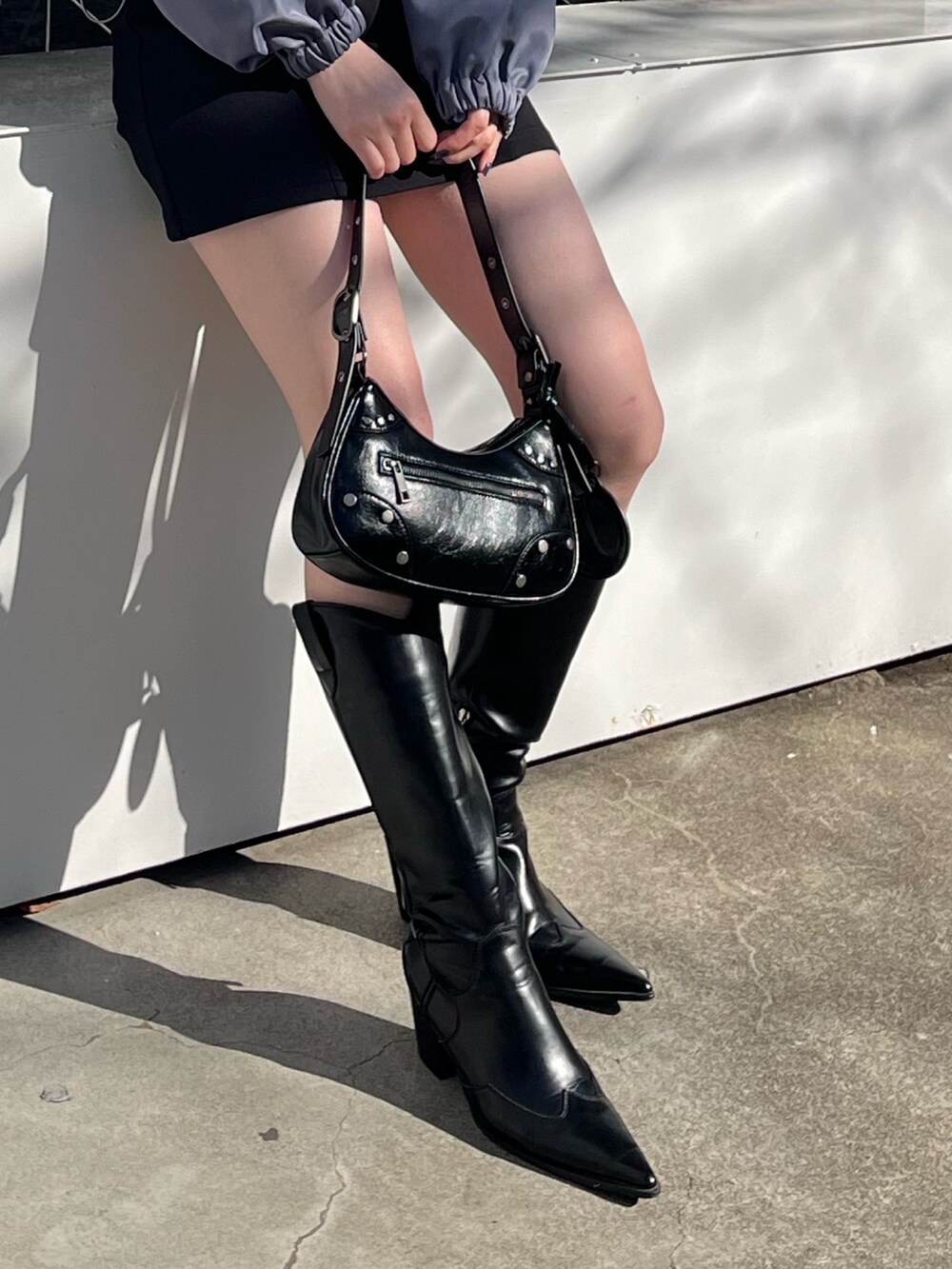 ブラック系のスカート、ブラック系のブーツ、ブラック系のハンドバッグを着用したレディースの冬コーディネートの7枚目の写真