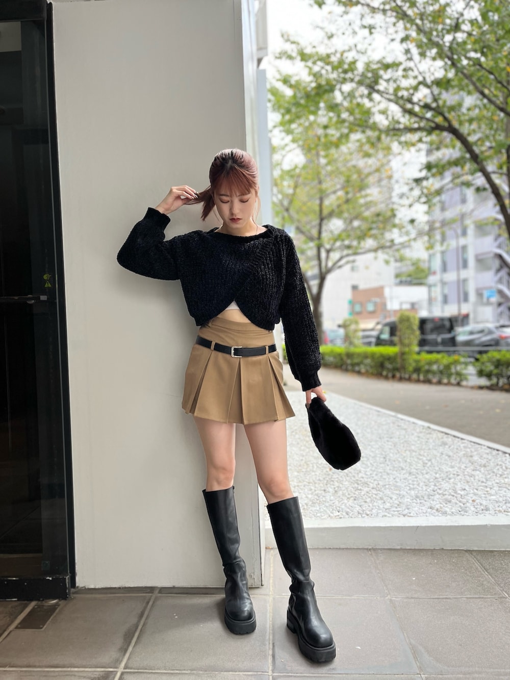 ブラック系のハンドバッグ、ブラック系のニット/セーター、ベージュ系のスカートを着用したレディースの秋コーディネートの2枚目の写真