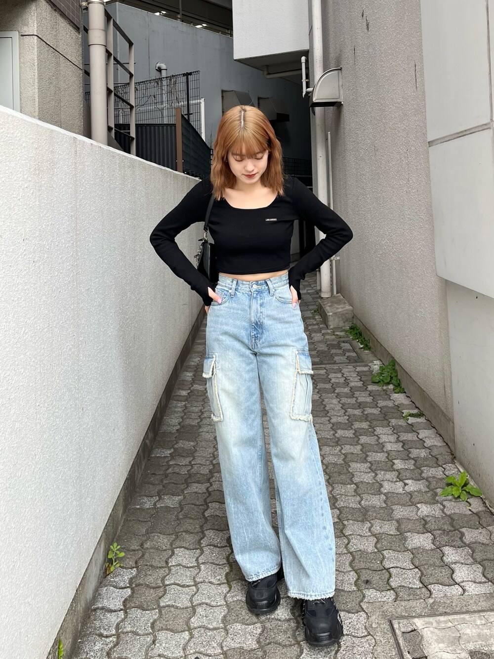 ブラック系のTシャツ/カットソー、ブラック系のスニーカー、ブルー系のデニムパンツを着用したレディースの春コーディネートの2枚目の写真