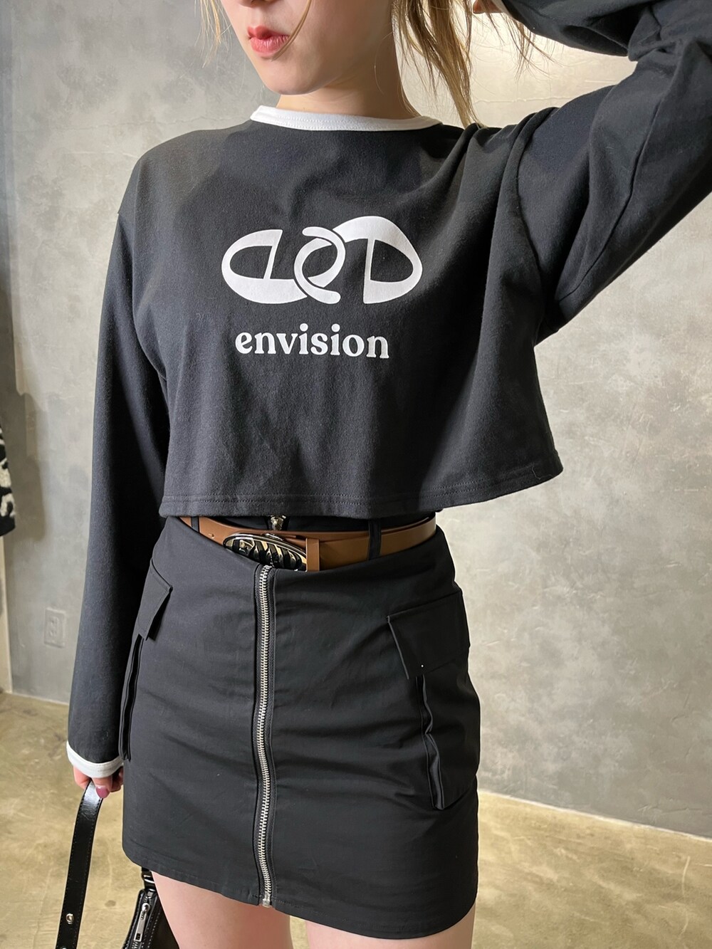 ブラック系のスカート、ブラウン系のブーツ、ブラック系のTシャツ/カットソーを着用したレディースの冬コーディネートの4枚目の写真