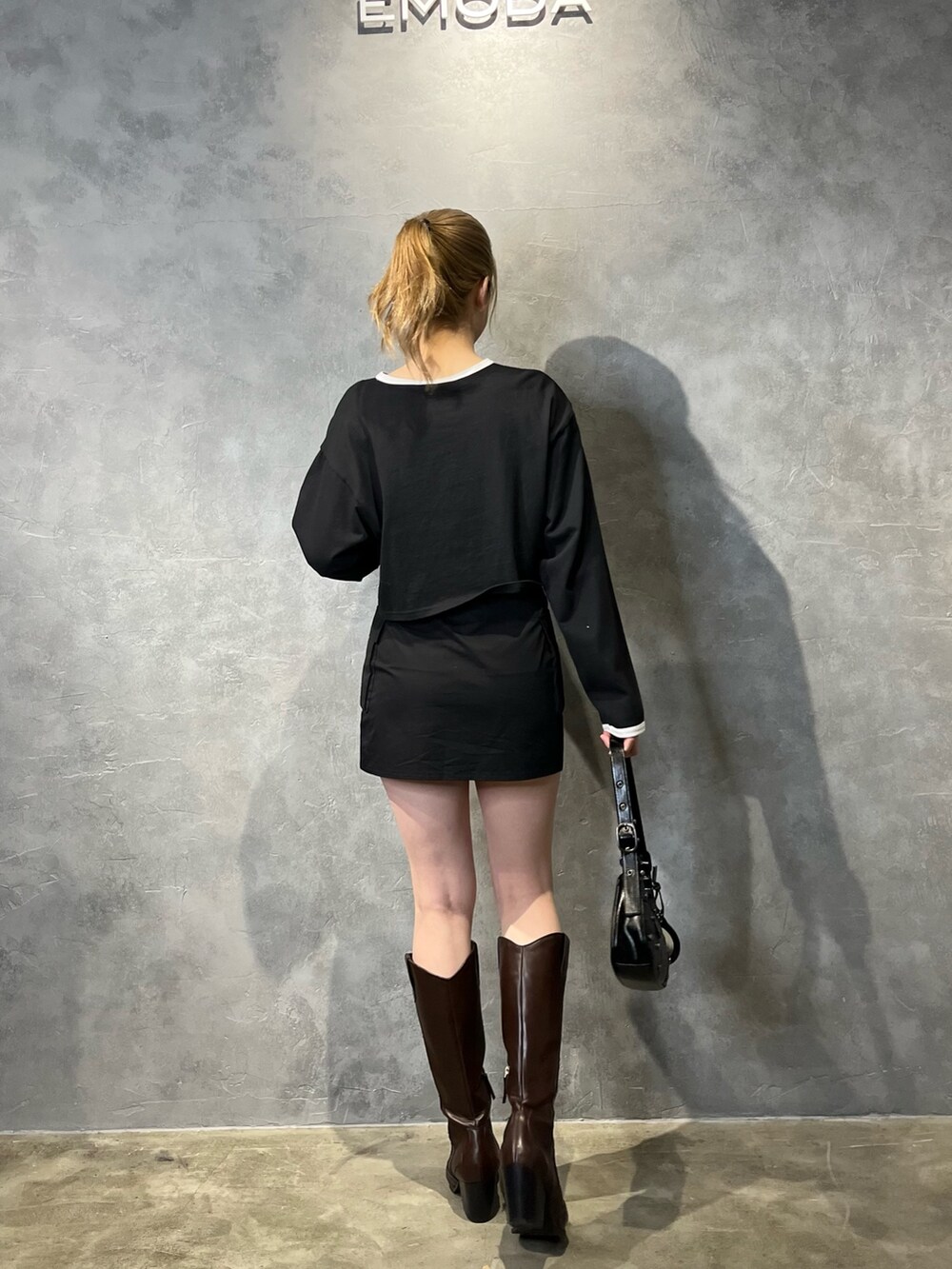 ブラック系のスカート、ブラウン系のブーツ、ブラック系のTシャツ/カットソーを着用したレディースの冬コーディネートの3枚目の写真