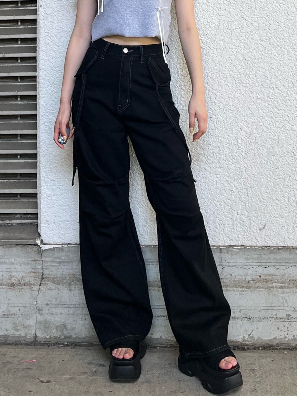 ブラック系のデニムパンツ、グレー系のTシャツ/カットソー、ブラック系のサンダルを着用したレディースの夏コーディネートの4枚目の写真