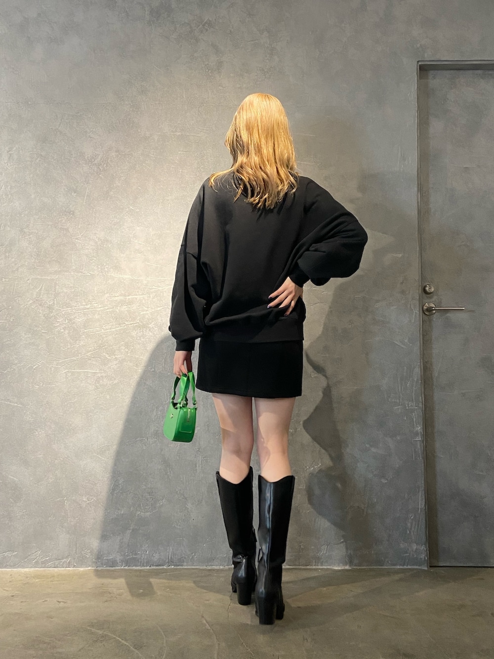 ブラック系のTシャツ/カットソー、ブラック系のブーツ、ブラック系のスカートを着用したレディースの冬コーディネートの5枚目の写真