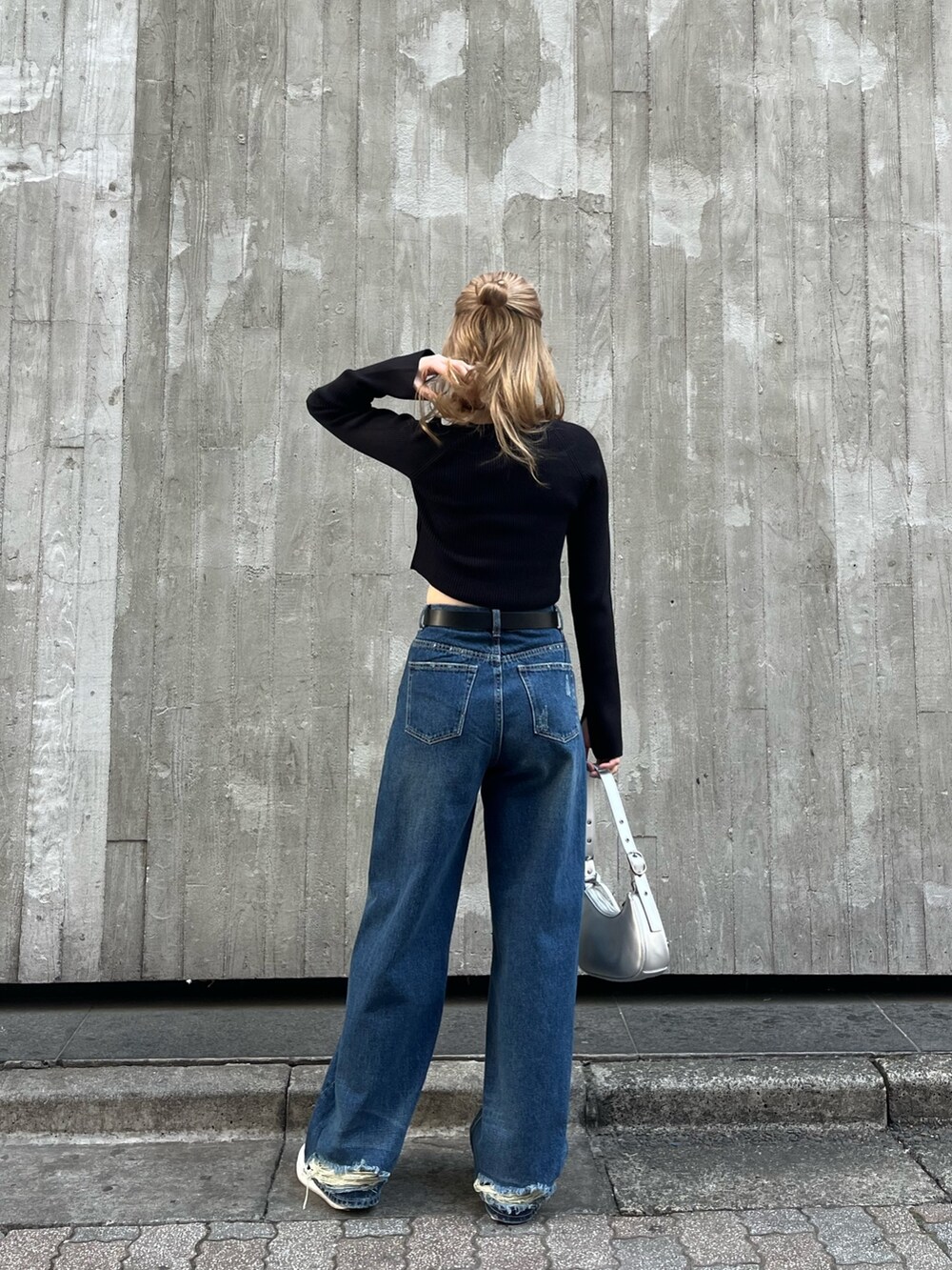 ブルー系のデニムパンツ、シルバー系のハンドバッグ、ブラック系のニット/セーターを着用したレディースの春コーディネートの4枚目の写真