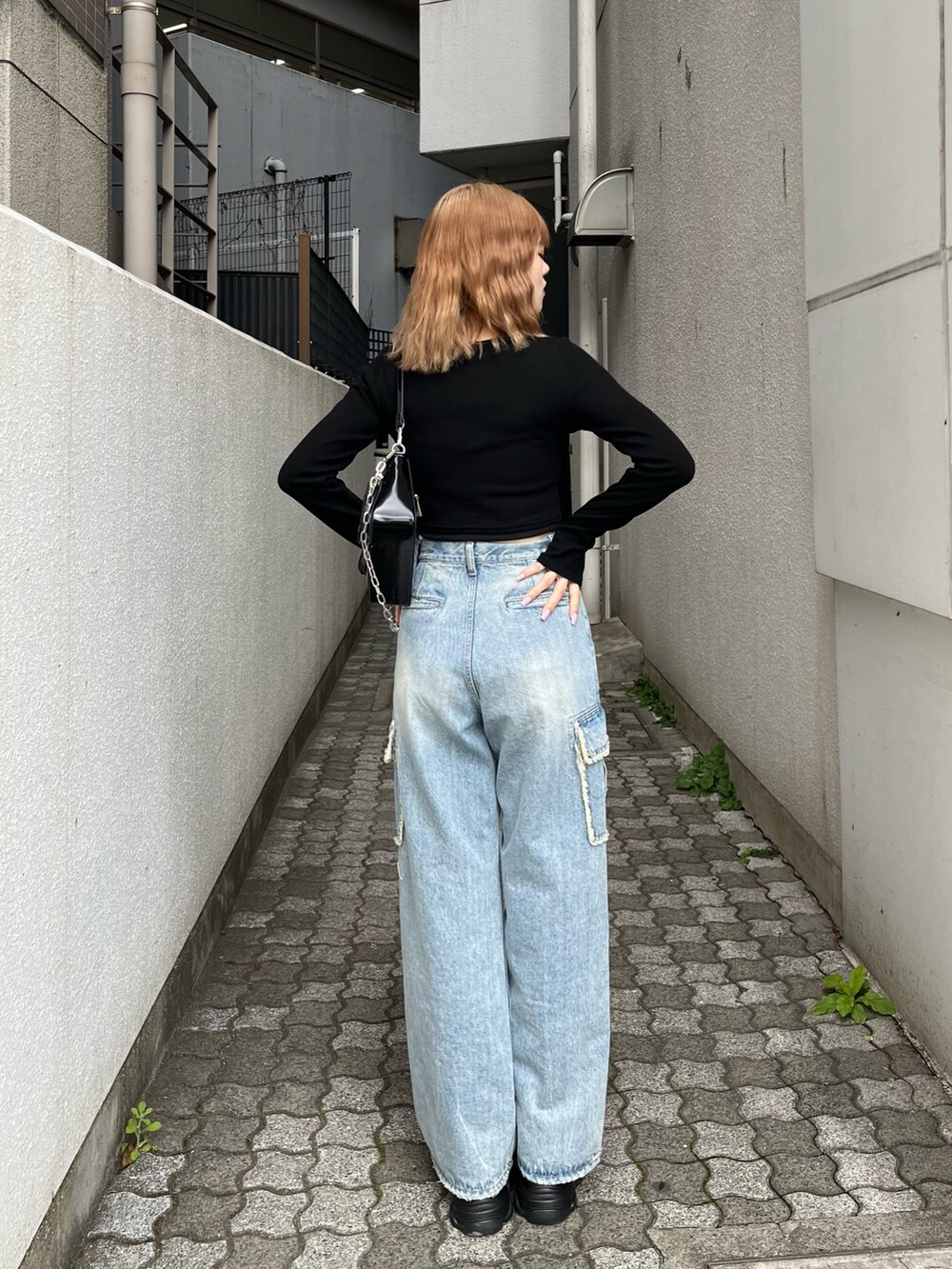 ブラック系のTシャツ/カットソー、ブラック系のスニーカー、ブルー系のデニムパンツを着用したレディースの春コーディネートの5枚目の写真