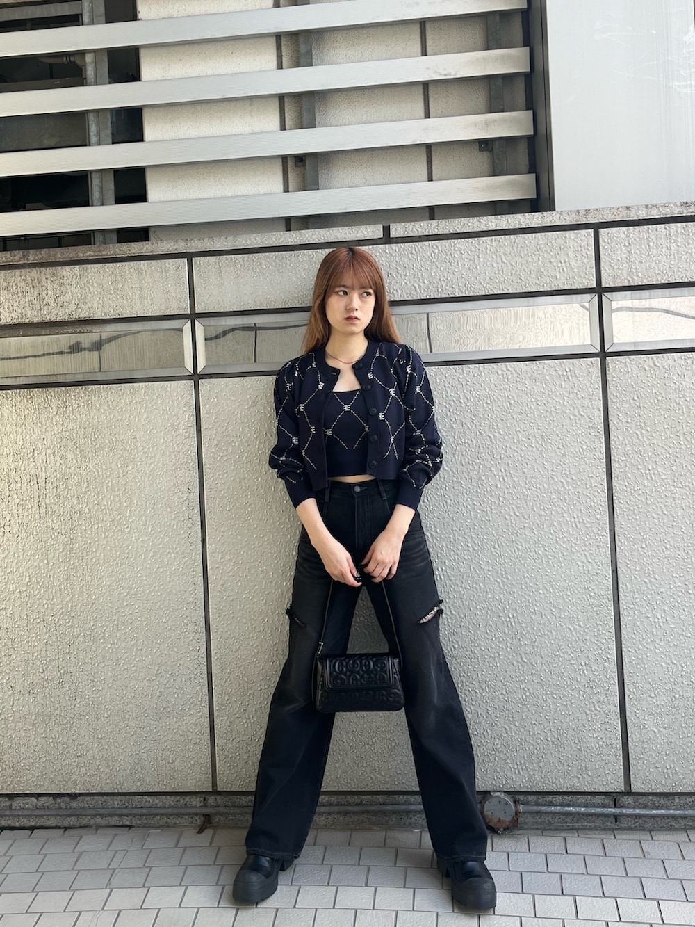 ブラック系のハンドバッグ、ブルー系のニット/セーター、ブラック系のブーツを着用したレディースの秋コーディネートの2枚目の写真