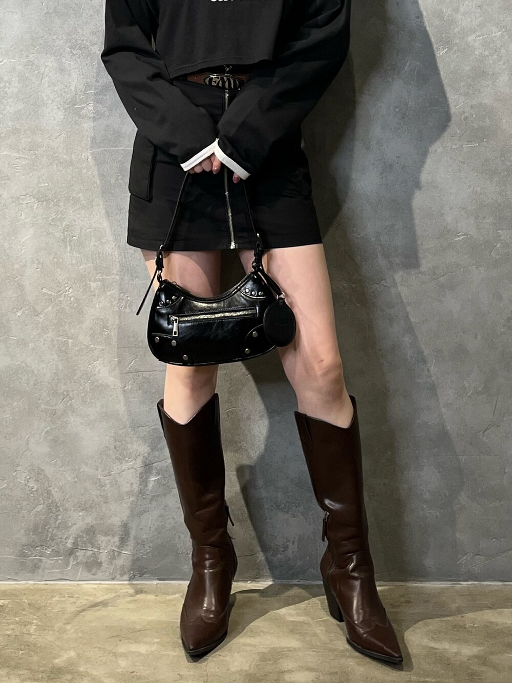 ブラック系のスカート、ブラウン系のブーツ、ブラック系のTシャツ/カットソーを着用したレディースの冬コーディネートの7枚目の写真