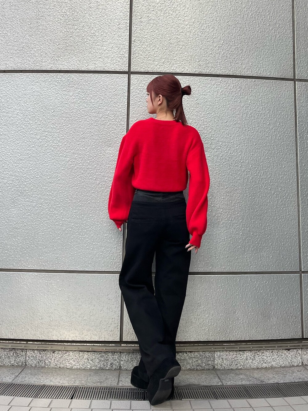 レッド系のニット/セーター、ブラック系のデニムパンツ、ブラック系のブーツを着用したレディースの冬コーディネートの4枚目の写真