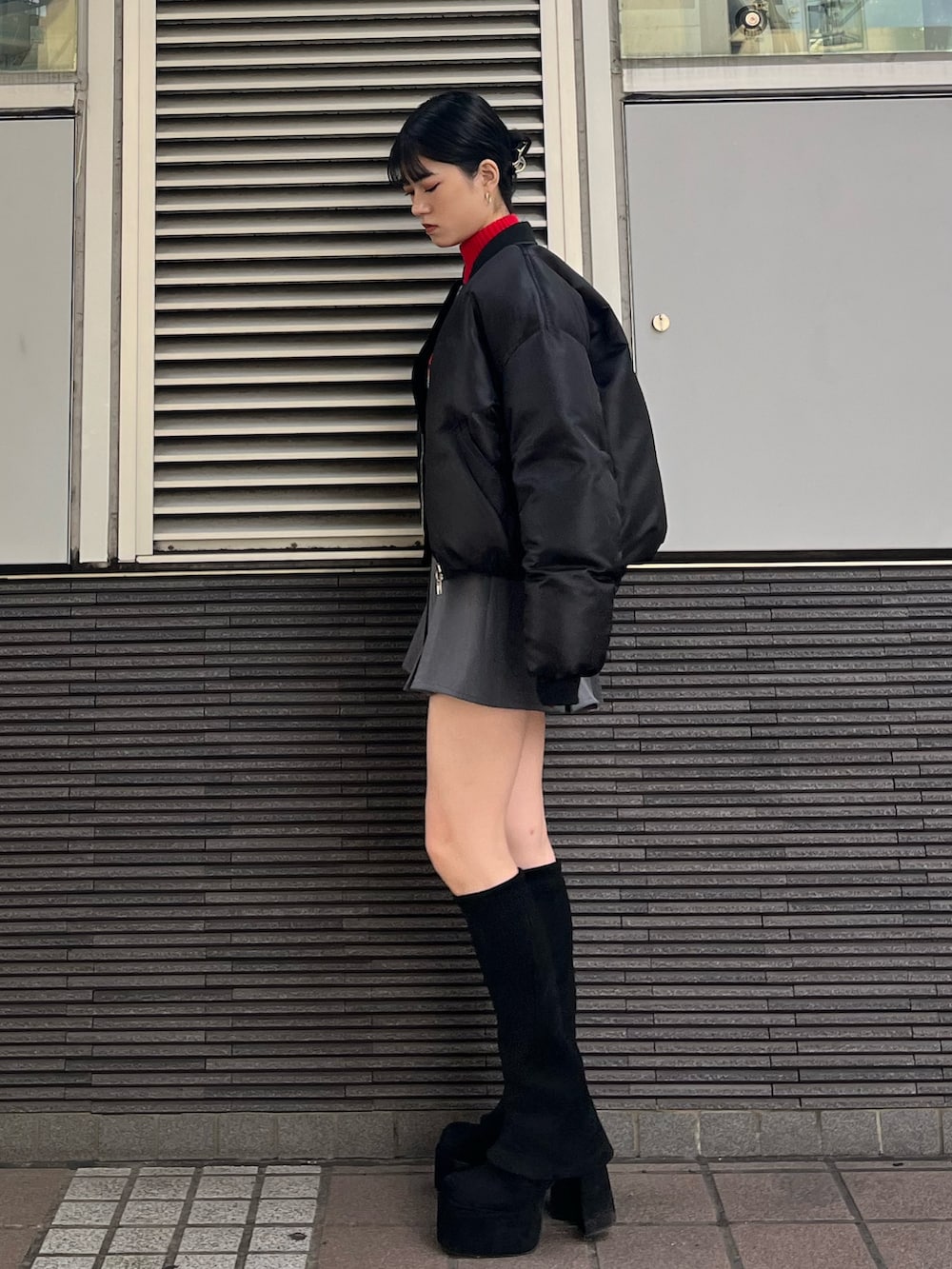 グレー系のスカート、レッド系のニット/セーター、ブラック系のブーツを着用したレディースの秋コーディネートの3枚目の写真