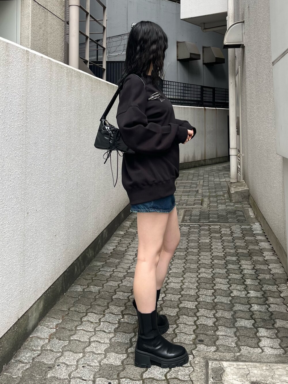 ブラック系のブーツ、ブラック系のショルダーバッグ、ブラック系のスウェットを着用したレディースの夏コーディネートの3枚目の写真