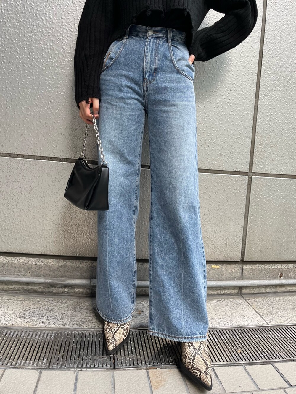 ブルー系のデニムパンツ、ブラック系のニット/セーター、ブラック系のハンドバッグを着用したレディースの秋コーディネートの5枚目の写真