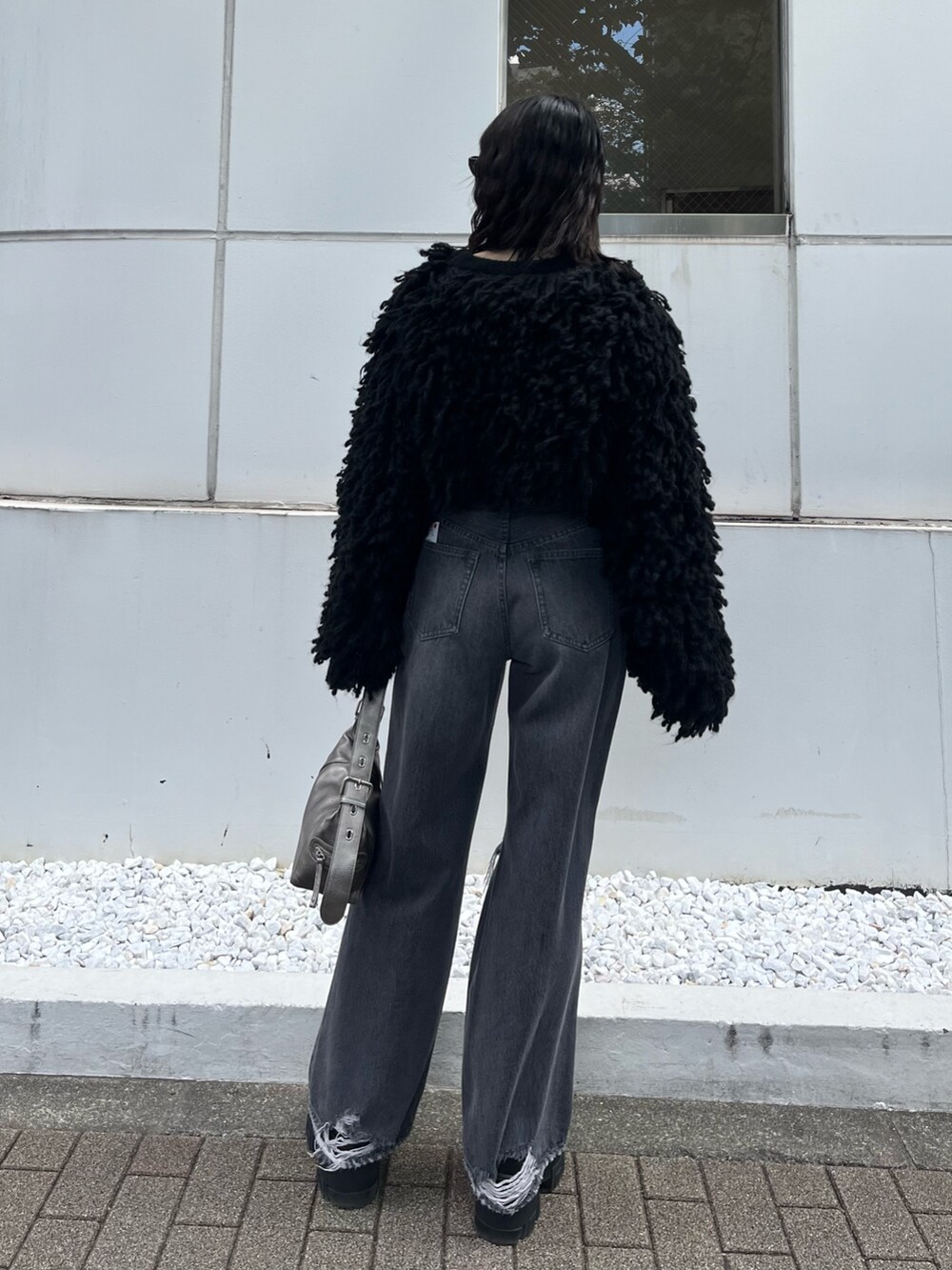 ブラック系のブーツ、グレー系のデニムパンツ、ブラック系のニット/セーターを着用したレディースの秋コーディネートの4枚目の写真