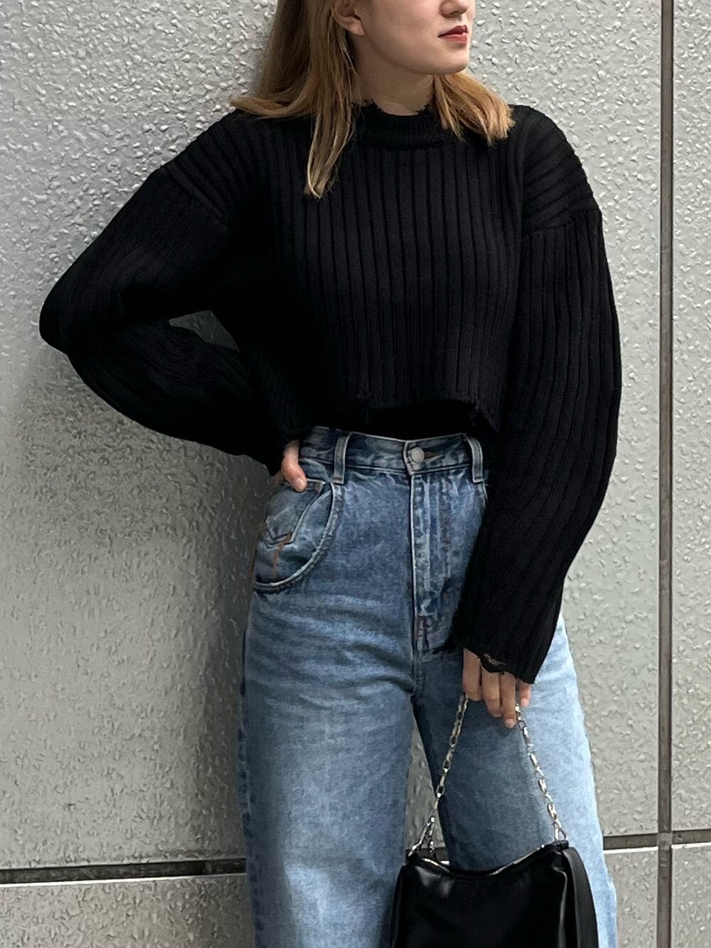 ブルー系のデニムパンツ、ブラック系のニット/セーター、ブラック系のハンドバッグを着用したレディースの秋コーディネートの7枚目の写真