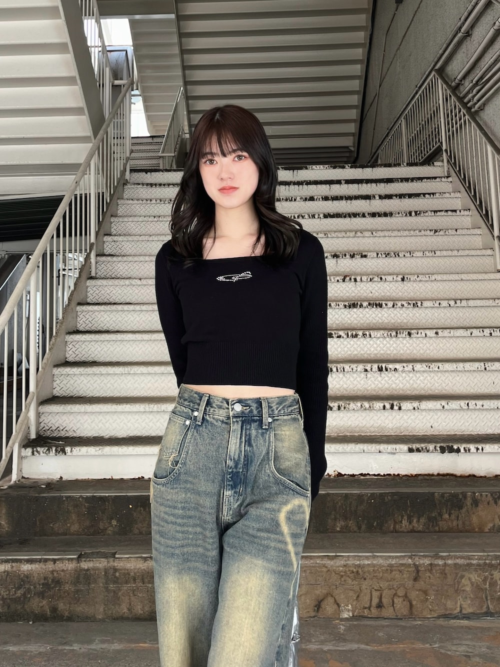 シルバー系のボストンバッグ、ブルー系のデニムパンツ、ブラック系のニット/セーターを着用したレディースの冬コーディネートの5枚目の写真