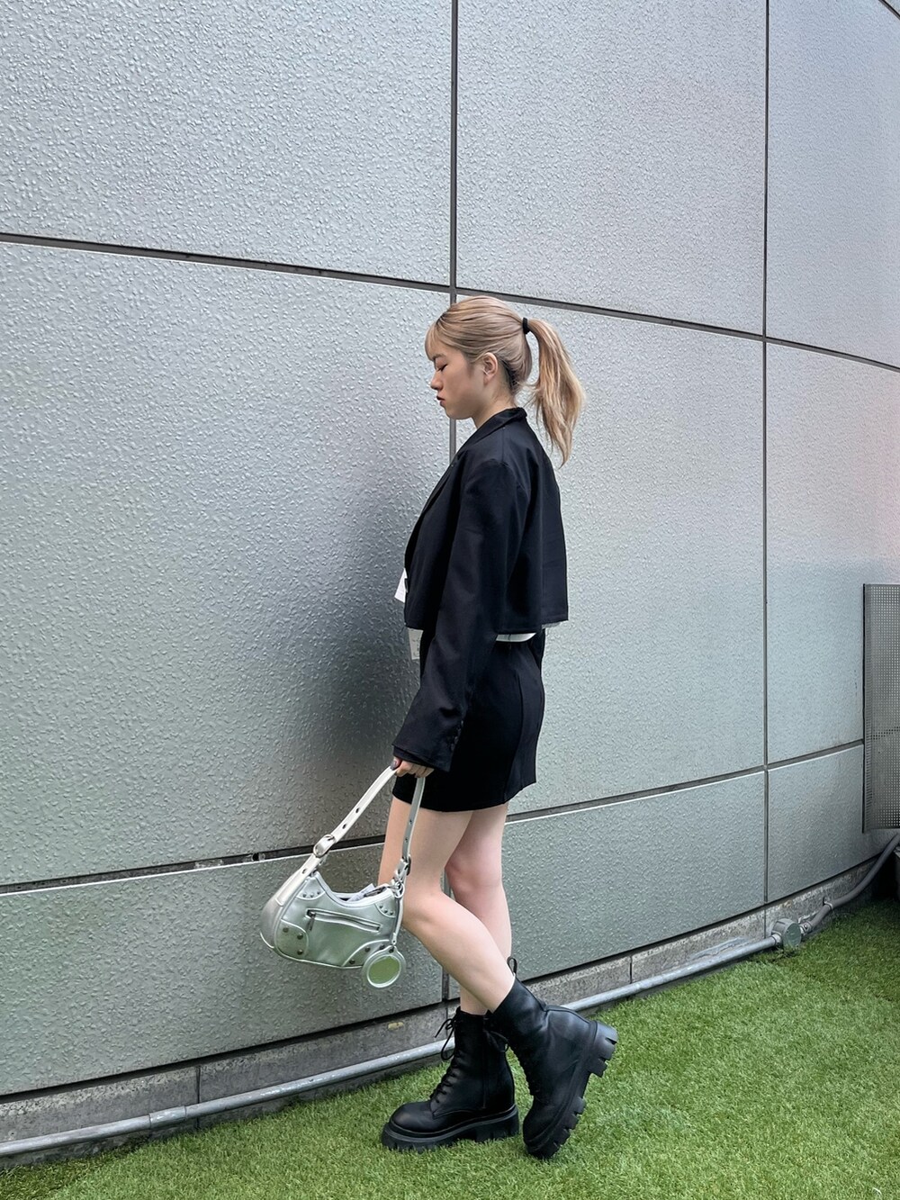 ブラック系のブーツ、シルバー系のハンドバッグ、ブラック系のテーラードジャケットを着用したレディースの春コーディネートの2枚目の写真