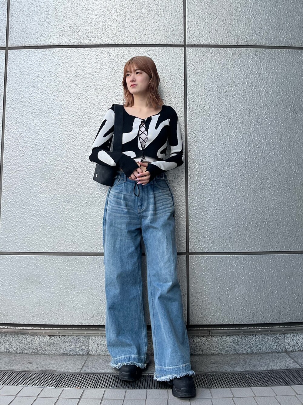 ブラック系のスニーカー、ブルー系のデニムパンツ、ホワイト系のキャミソールを着用したレディースの冬コーディネートの3枚目の写真