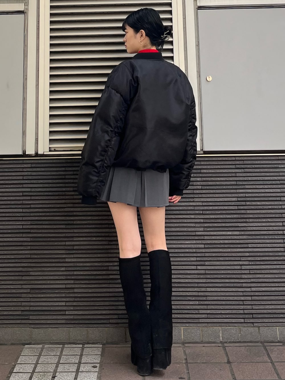 グレー系のスカート、レッド系のニット/セーター、ブラック系のブーツを着用したレディースの秋コーディネートの4枚目の写真