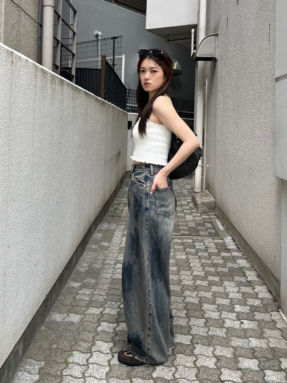 ブルー系のデニムパンツ、ブラウン系のスニーカー、ホワイト系のキャミソールを着用したレディースの春コーディネートの2枚目の写真