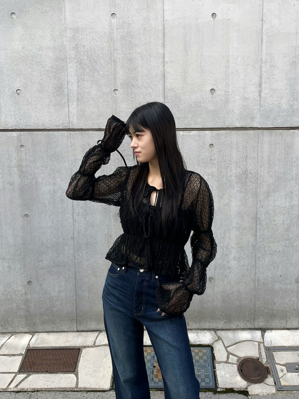 ブルー系のデニムパンツ、ブラック系のニット/セーター、ブラック系のサンダルを着用したレディースの春コーディネートの3枚目の写真