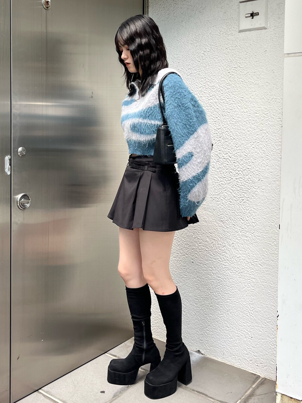 ブラック系のショルダーバッグ、ブラック系のスカート、その他のブーツを着用したレディースの秋コーディネートの2枚目の写真