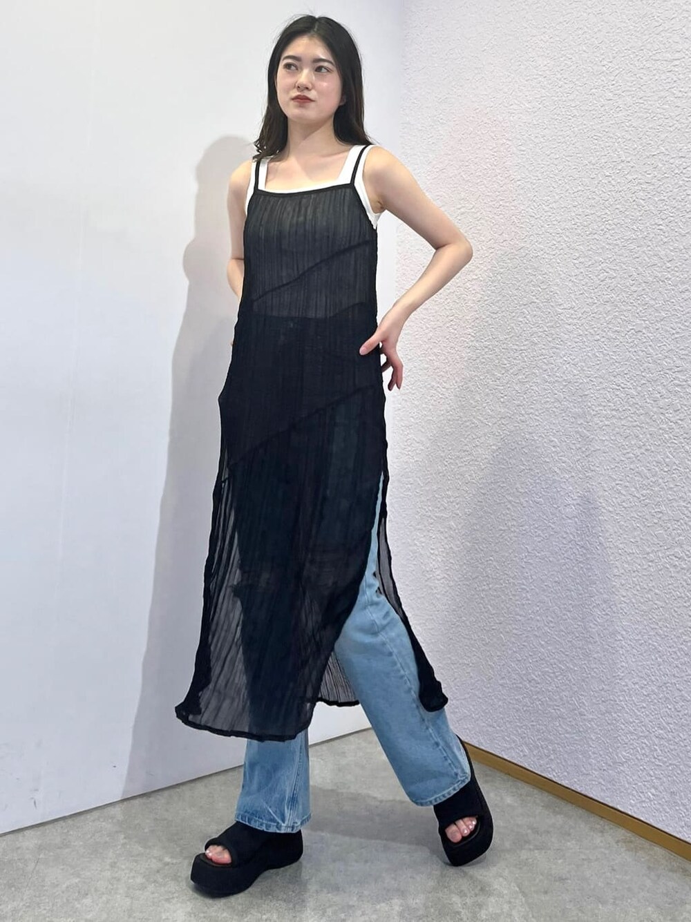 ホワイト系のタンクトップ、ブラック系のワンピース、ブルー系のデニムパンツを着用したレディースの夏コーディネートの2枚目の写真