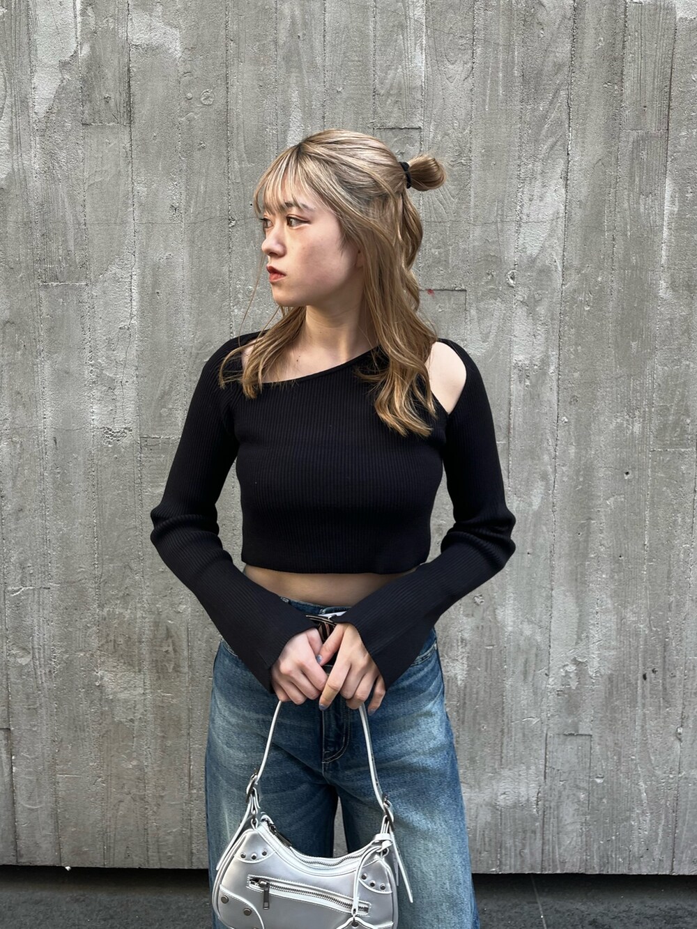 ブルー系のデニムパンツ、シルバー系のハンドバッグ、ブラック系のニット/セーターを着用したレディースの春コーディネートの5枚目の写真