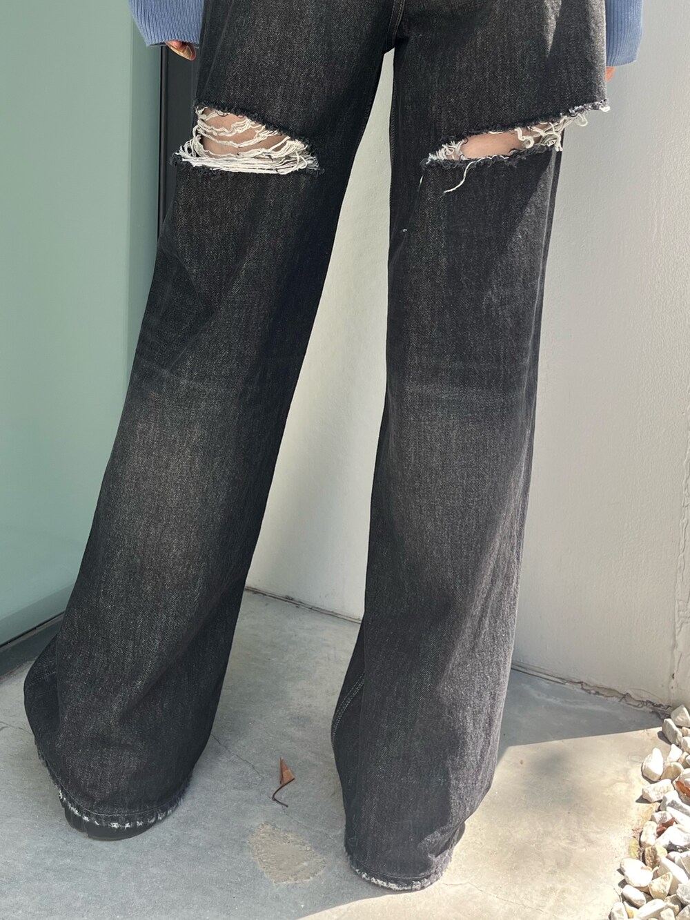 ブラック系のデニムパンツ、ブラック系のブーツ、ブルー系のニット/セーターを着用したレディースの秋コーディネートの5枚目の写真