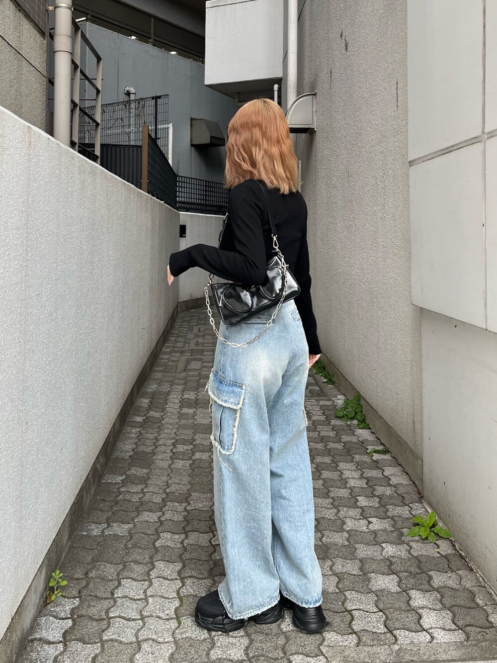 ブラック系のTシャツ/カットソー、ブラック系のスニーカー、ブルー系のデニムパンツを着用したレディースの春コーディネートの4枚目の写真