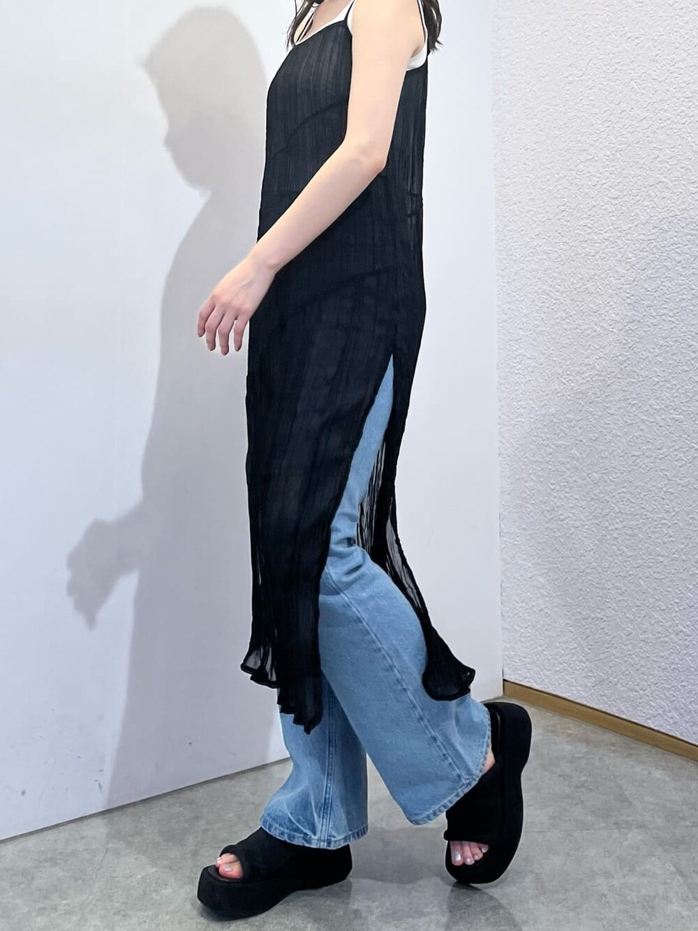 ホワイト系のタンクトップ、ブラック系のワンピース、ブルー系のデニムパンツを着用したレディースの夏コーディネートの3枚目の写真